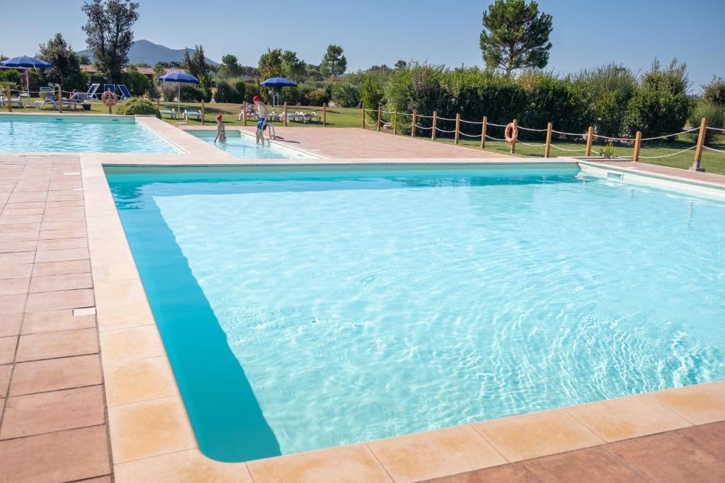 a large swimming pool with blue water at Residenza Principina in Principina Terra