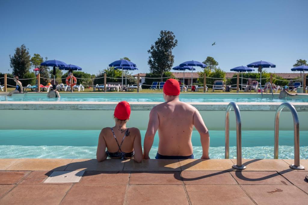 a man and woman sitting in the water at a pool at Residenza Principina in Principina Terra