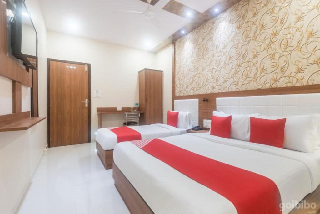 two beds in a hotel room with red and white sheets at Hotel Durga Elite Mumbai in Mumbai