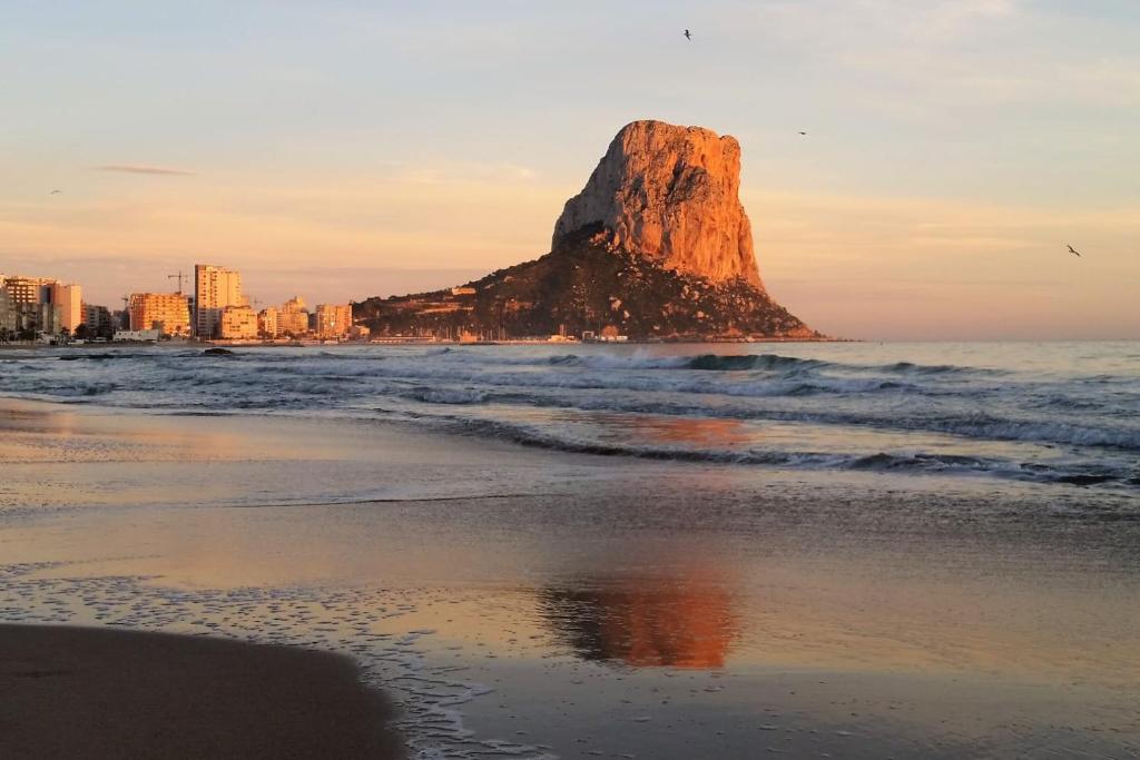 a rock in the ocean next to a beach at Calpe Beach in Calpe