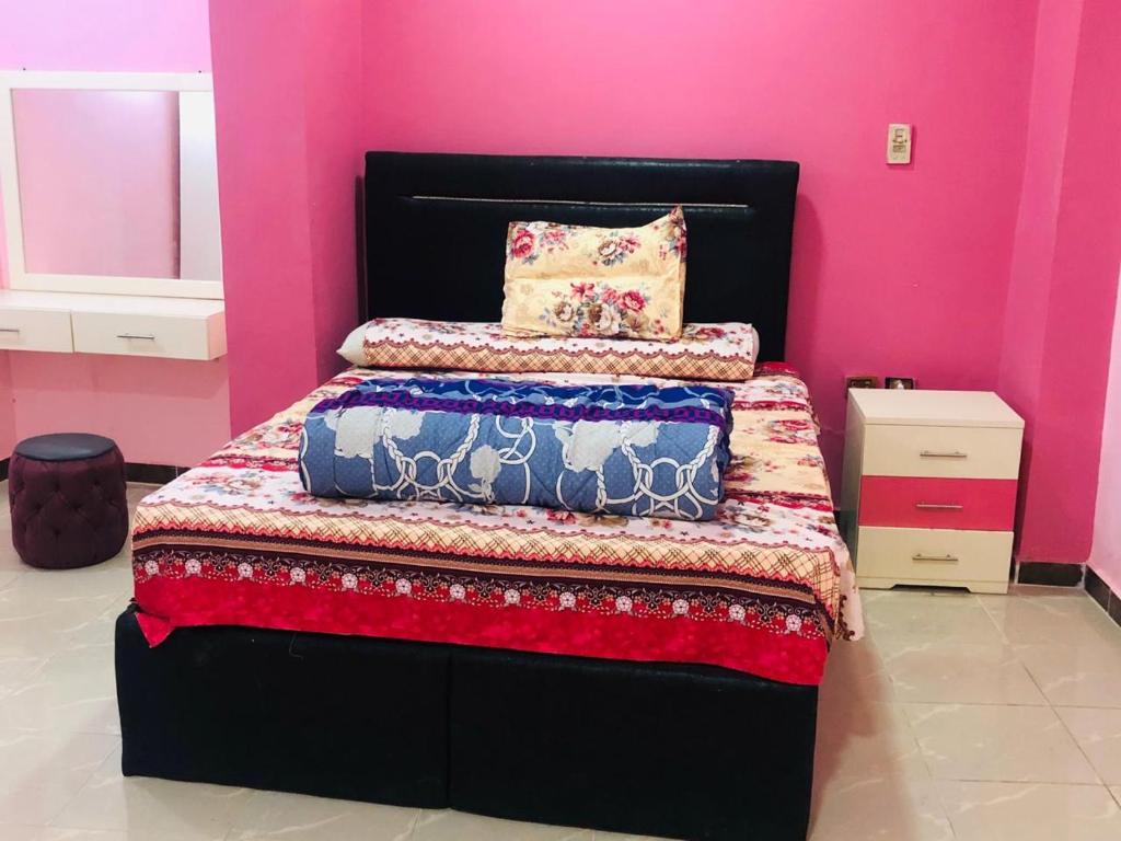 a bedroom with a black bed with a pink wall at Sweet Home- No Egyptian in Hurghada