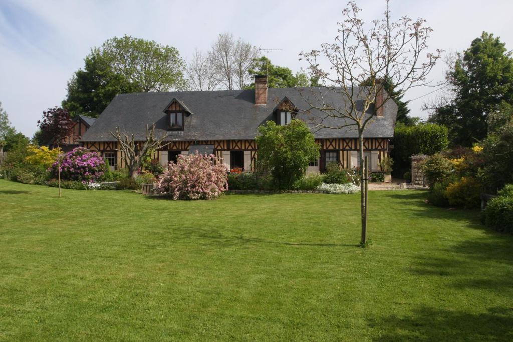 uma casa grande com um relvado verde em frente em La Main Ouverte em Fultot