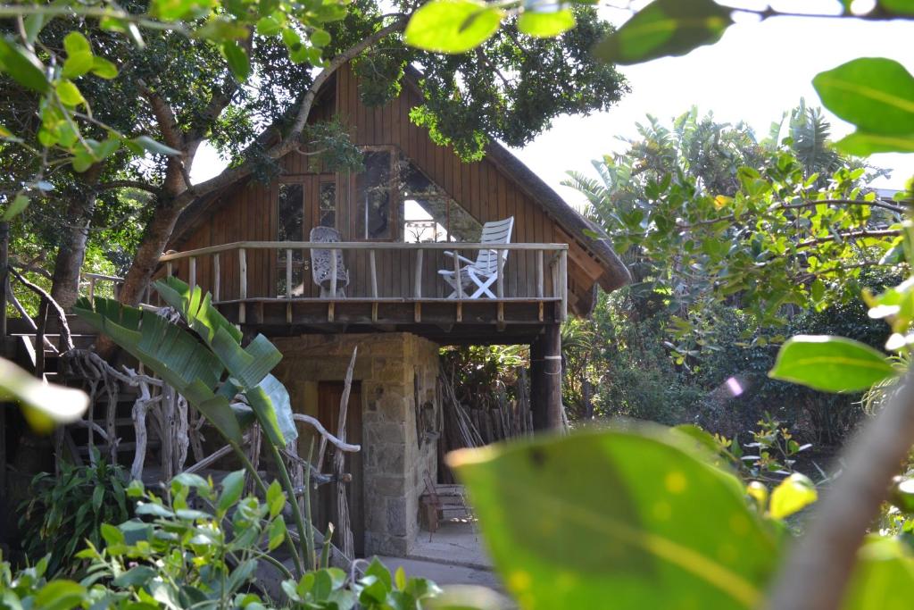 a tree house with a deck in the woods at Driftwood Treehouse in Sunrise-on-Sea
