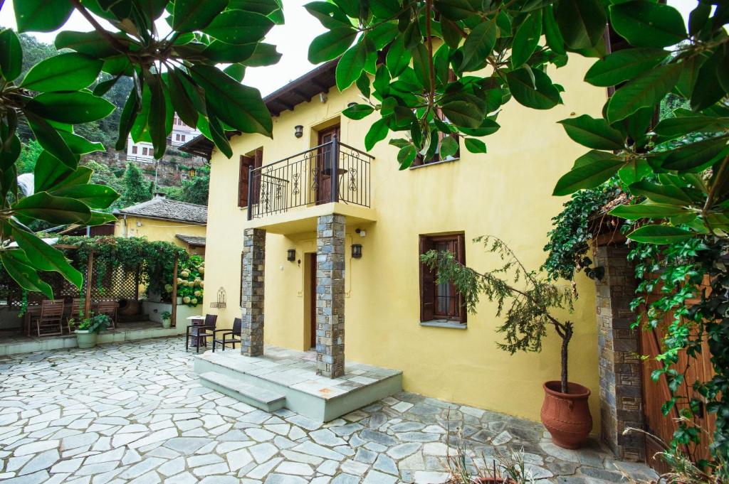 a yellow house with a balcony and a patio at Ellis Full Guest House in Tsagarada