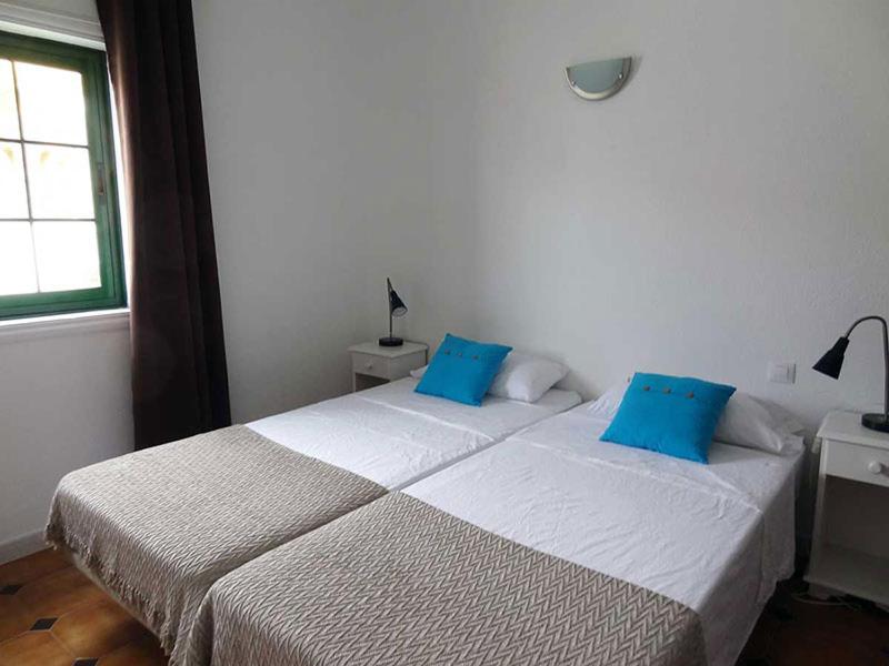 a bedroom with a large white bed with blue pillows at Costa Antigua in Costa de Antigua