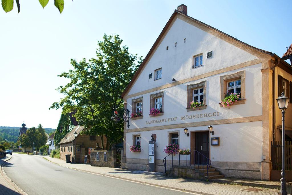 ein weißes Gebäude an der Straßenseite in der Unterkunft Landgasthof Mörsbergei in Bubenreuth