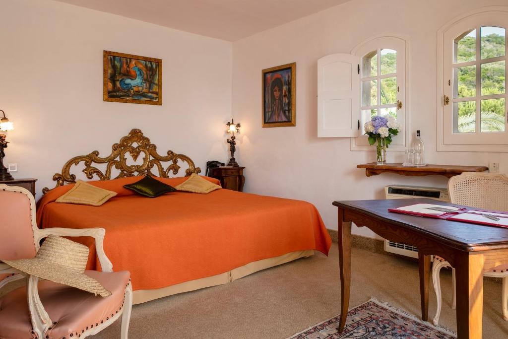a bedroom with an orange bed and a table at Hotel Le Maquis in Porticcio
