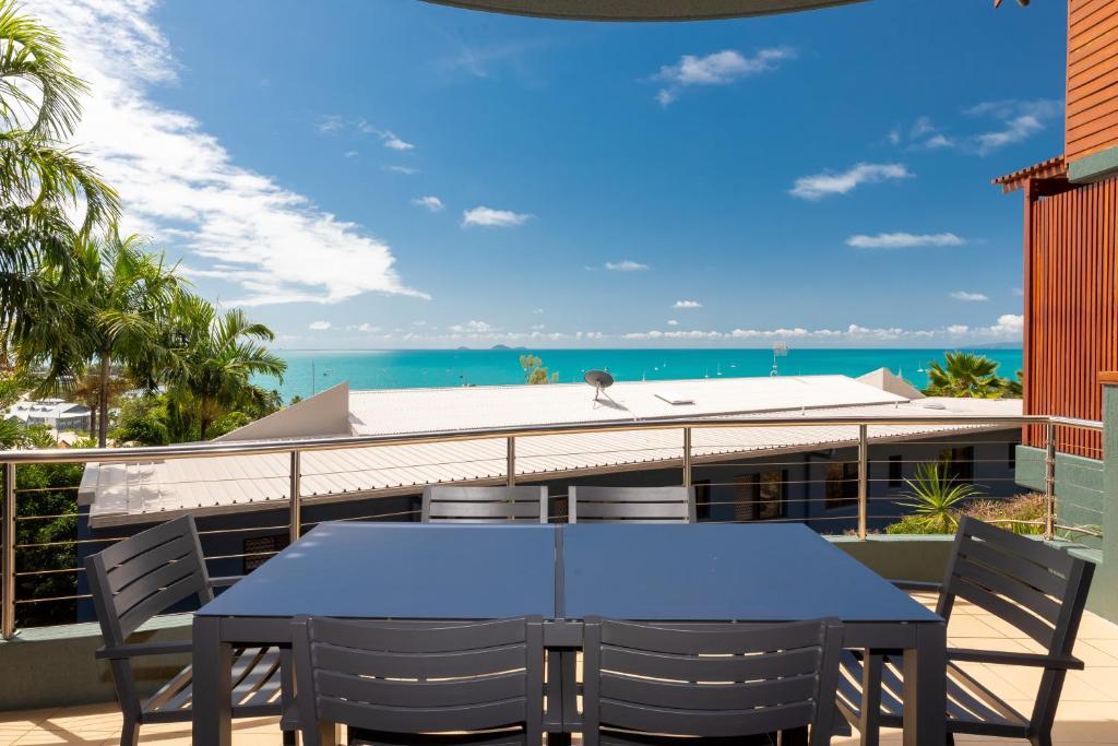 - une table bleue sur un balcon avec vue sur l'océan dans l'établissement Absolute Airlie, à Airlie Beach