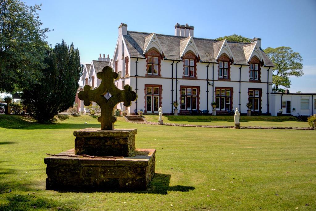 una estatua delante de una casa con una cruz en The Ennerdale Country House Hotel ‘A Bespoke Hotel’ en Cleator