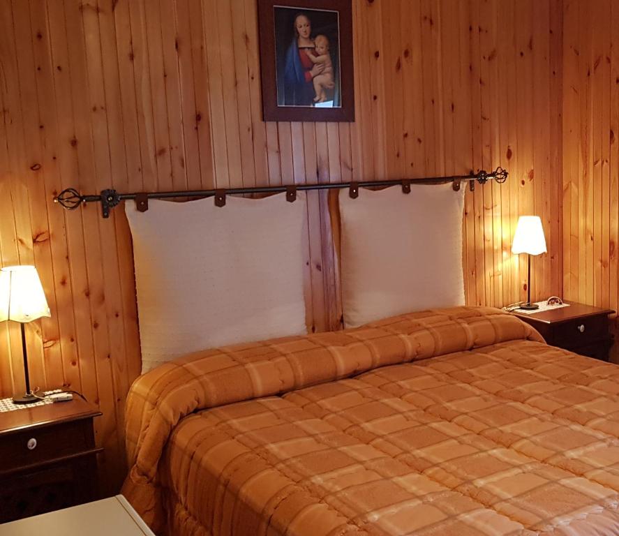 1 dormitorio con 1 cama con 2 lámparas y una foto en la pared en Charme & Relax a Rivisondoli, en Rivisondoli