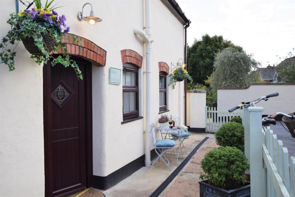 a white house with a brown door and a table at The Cottage in Exmouth