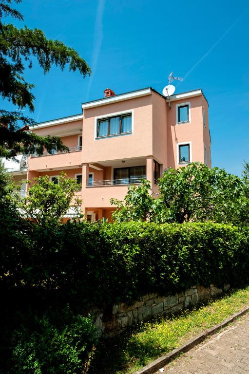 różowy budynek z krzakami przed nim w obiekcie Apartments Centener w Rovinj