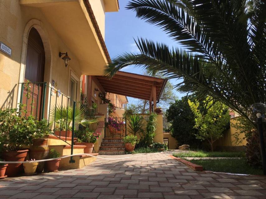 un edificio con un patio con plantas y una palmera en Villa Rahal, en Racalmuto