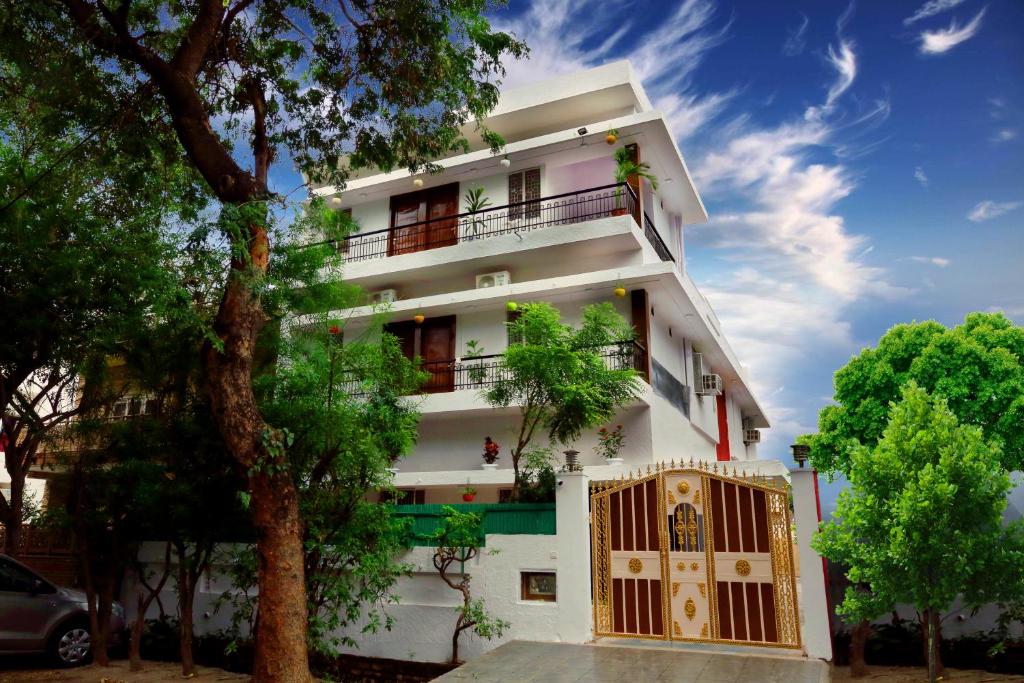 a white building with a gate and trees at Golden Homestay in New Delhi