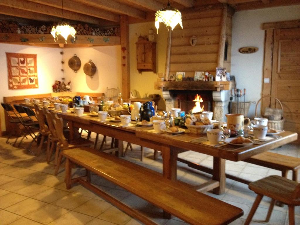 a long wooden table in a room with a fireplace at Les Pralets Plus in La Magne