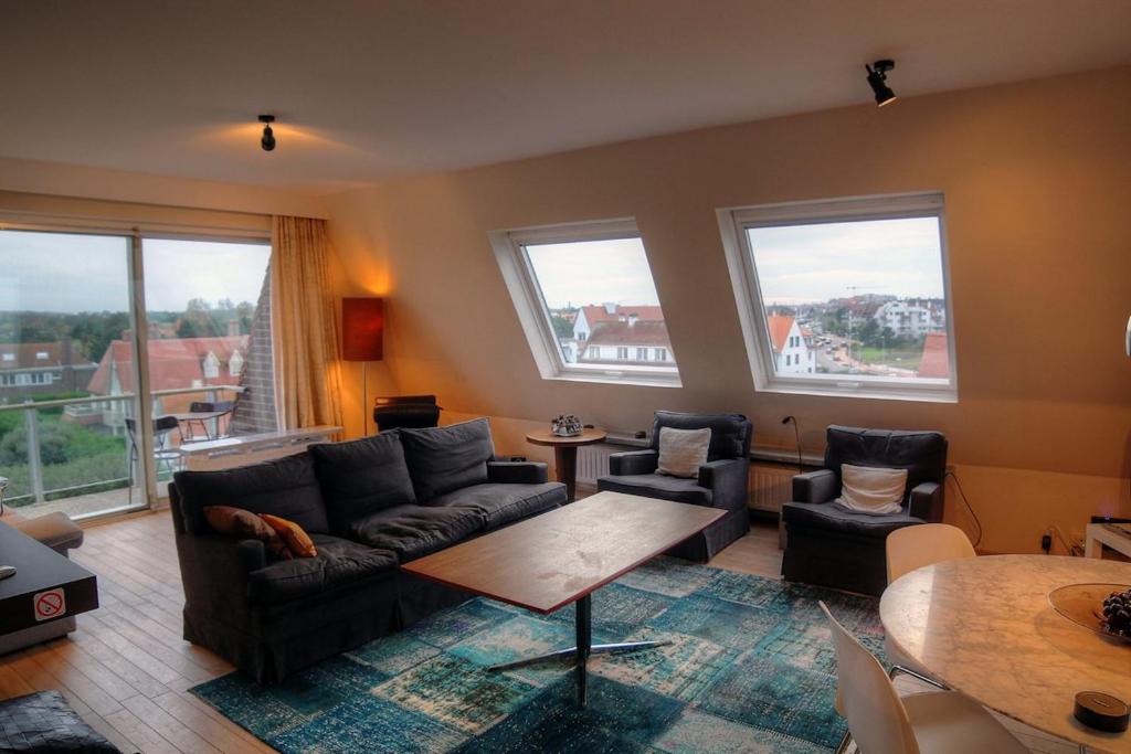 a living room with a couch and chairs and windows at Zoutezoute in Knokke-Heist