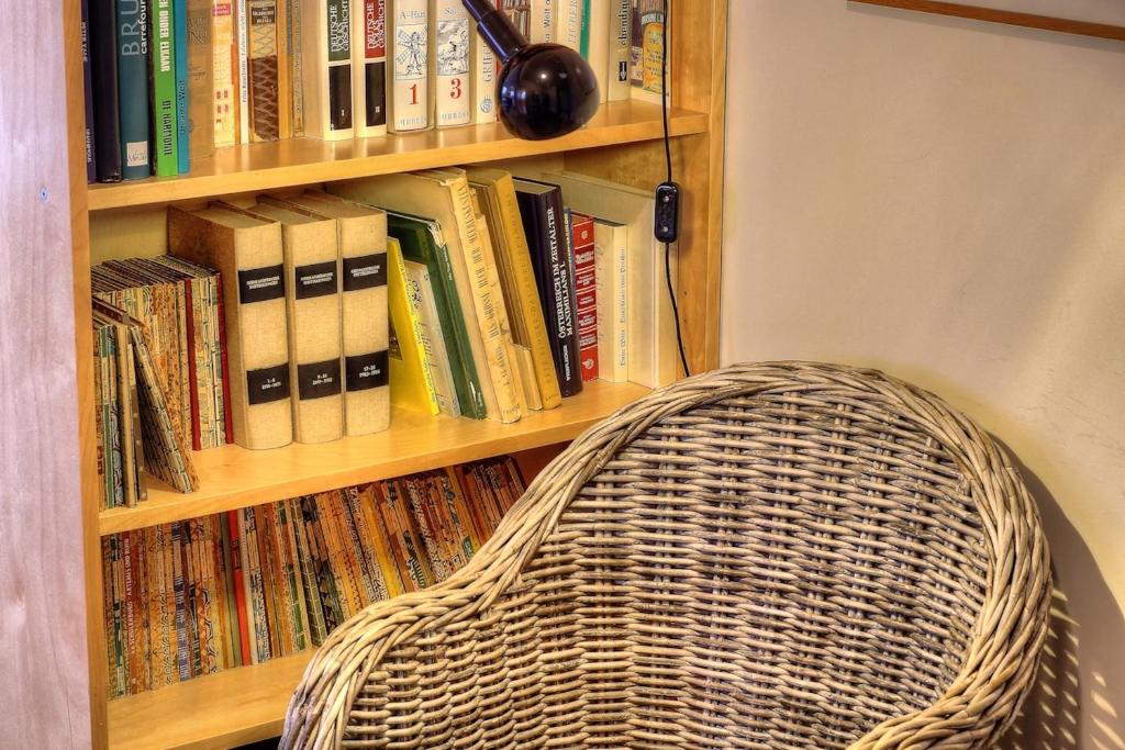 a book shelf filled with books and a wicker chair at Zoutezoute in Knokke-Heist