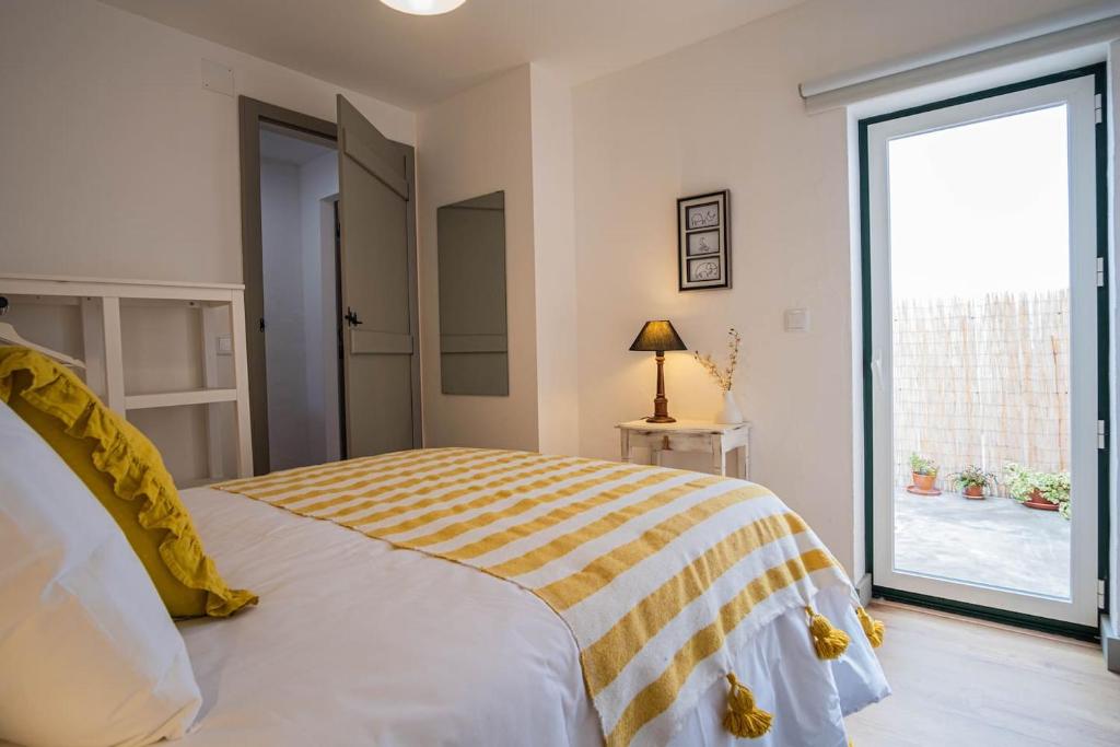 1 dormitorio con 1 cama con manta amarilla y blanca en Casa do Largo - Litle house by the vines en Alfeiria