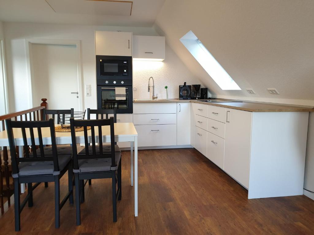a kitchen with white cabinets and a table and chairs at Ferienwohnung Marlena in Hage