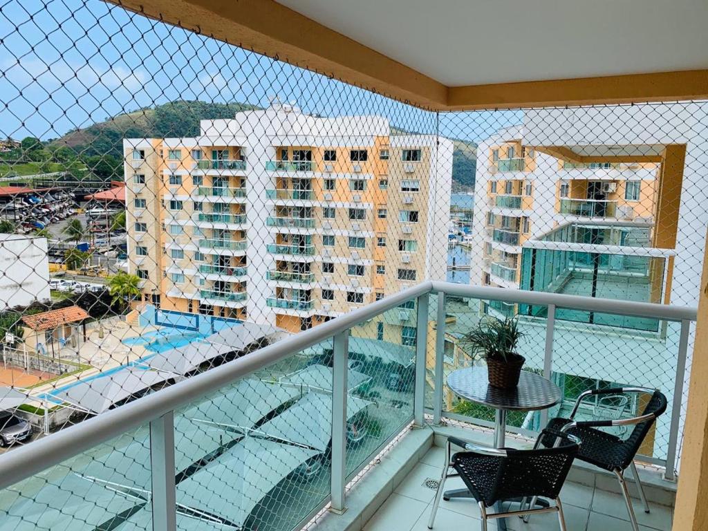 einen Balkon mit einem Tisch, Stühlen und Gebäuden in der Unterkunft Apartamento ao lado do shopping Piratas Angra dos Reis in Angra dos Reis