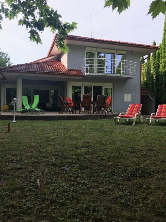 a house with red and green chairs in the yard at Megtart-lak Villa in Balatonszárszó