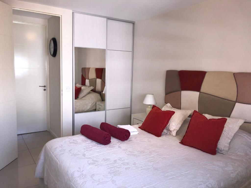 a bedroom with a large white bed with red pillows at Departamento boutique en nueva cordoba in Córdoba