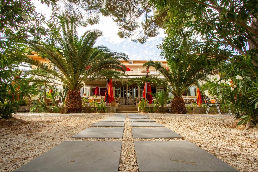 une passerelle devant un bâtiment planté de palmiers dans l'établissement Hotel Le Ceinturon, à Hyères