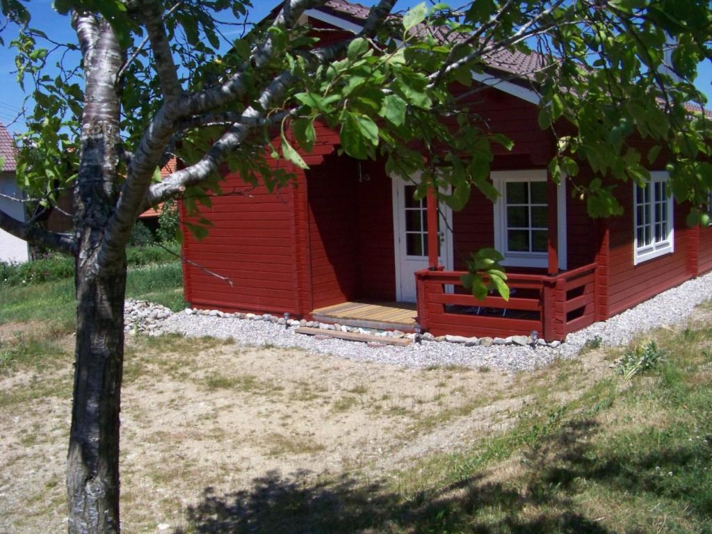 a red house with a teddy bear sitting on the porch at Ferienhaus Brunnenweiher in Kißlegg