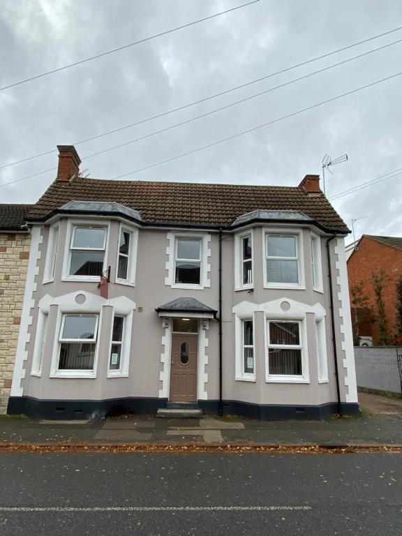 uma casa branca com uma porta castanha numa rua em Abbey Guest House em Milton Keynes