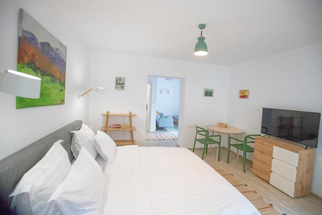 um quarto branco com uma cama e uma televisão em Brasha Residence em Brasov