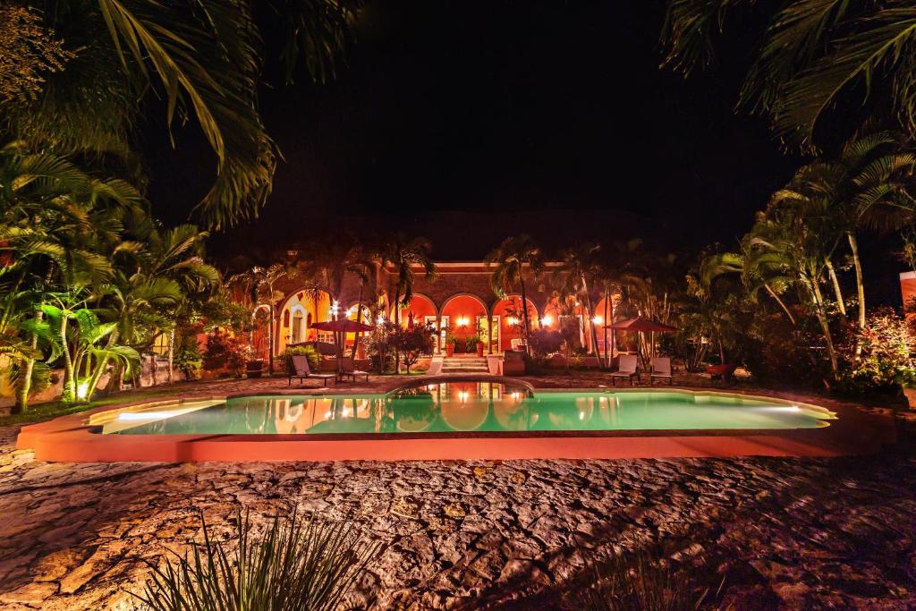 a swimming pool in front of a house at night at Hacienda Sacnicte in Izamal