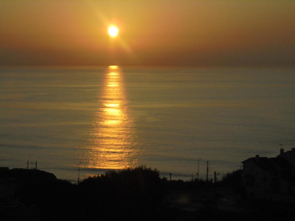 a sunset over the ocean with the sun reflecting on the water at Ericeira Sunset Apartment in Ericeira