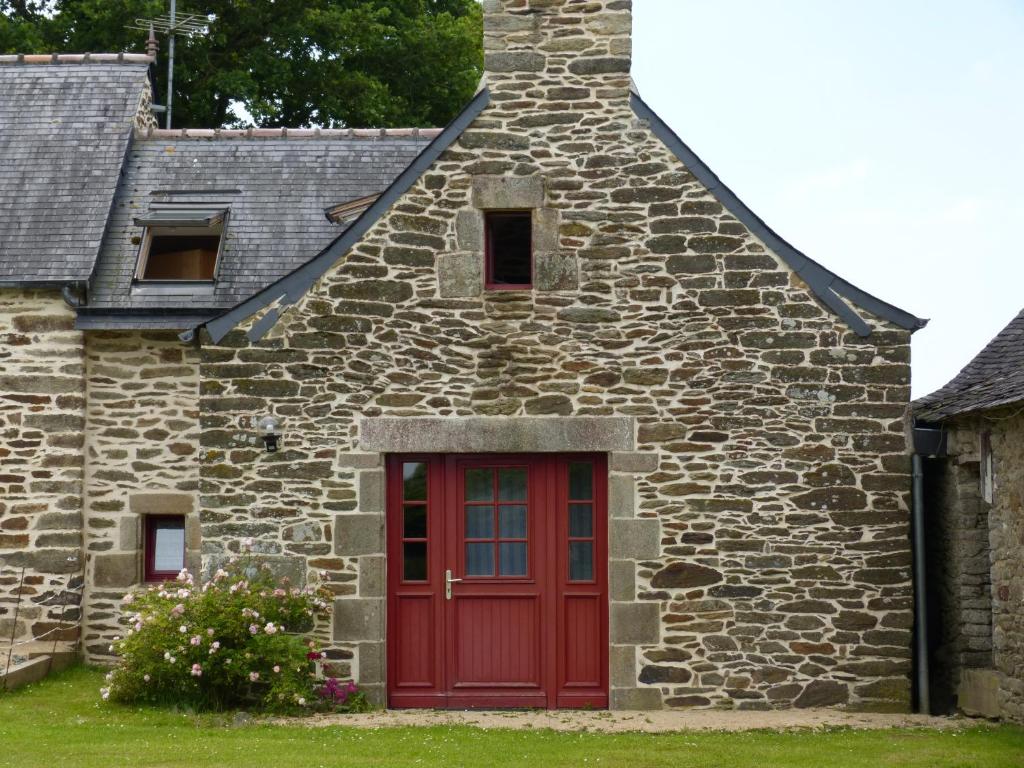 Lopérec的住宿－GITE DE CARACTERE，一座古老的石头建筑,设有红色的门