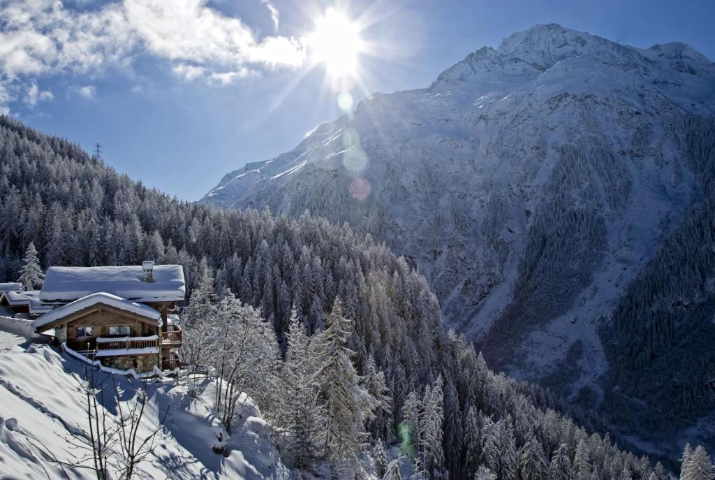 una montaña cubierta de nieve con el sol brillando en una cabaña en Chalet Rocher, en La Thuile Sainte-Foy-Tarentaise