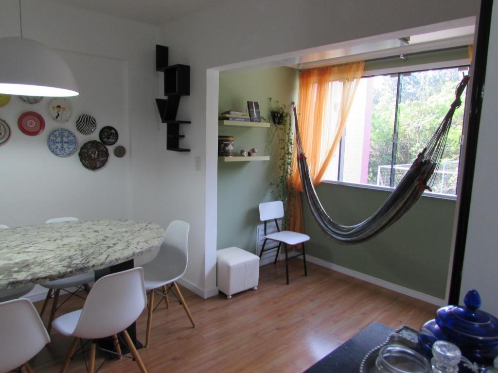 a dining room with a table and a hammock hanging from a window at Apê da Gabi in Balneário Camboriú