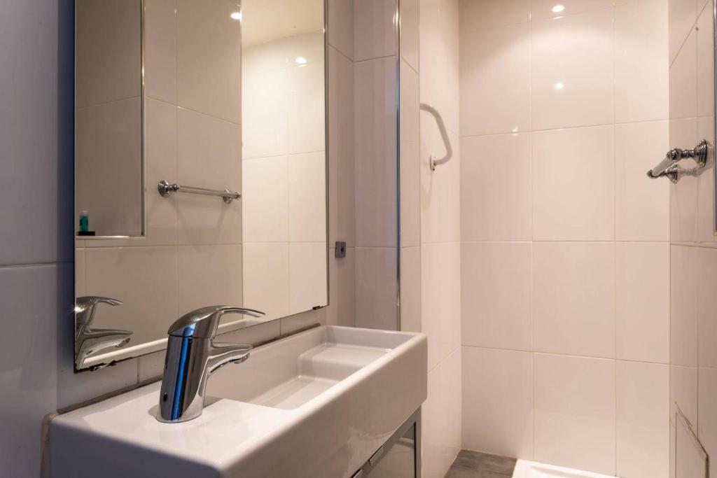 a white bathroom with a sink and a shower at Hôtel Le Mistral in Marseille