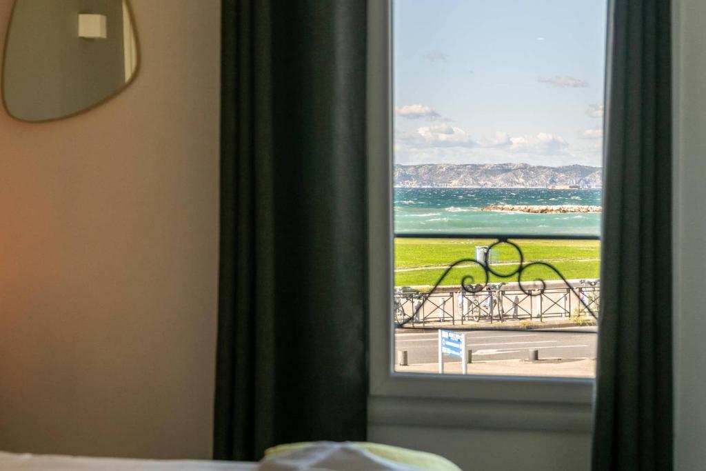 a room with a window with a view of the ocean at Hôtel Le Mistral in Marseille