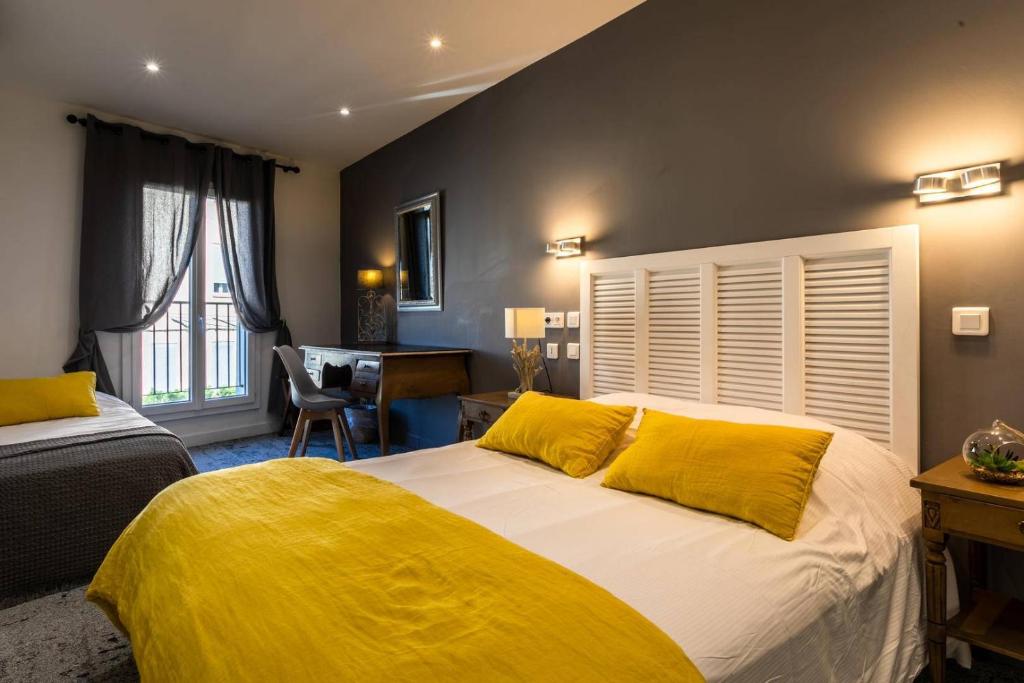 a bedroom with a large bed with yellow pillows at Hôtel Le Mistral in Marseille
