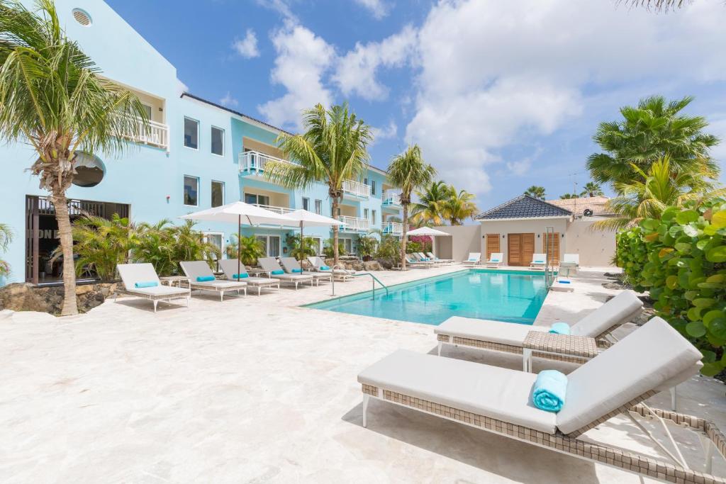 a villa with a swimming pool and palm trees at Dolphin Suites & Wellness Curacao in Willemstad
