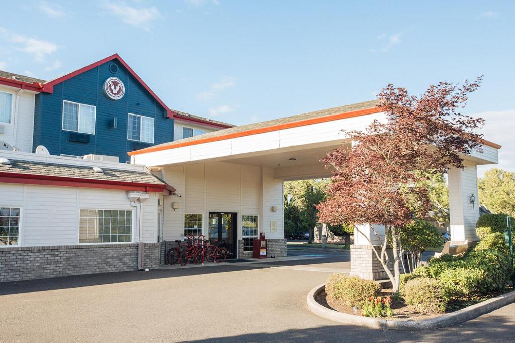 マクミンヴィルにあるRed Lion Inn & Suites McMinnvilleの青い建物と木のあるガソリンスタンド