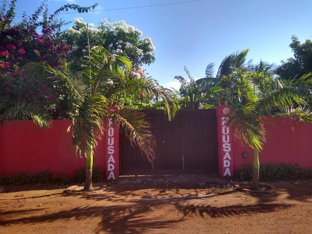a fence with two palm trees in front of it at Pousada Vila Sol in São Miguel do Gostoso