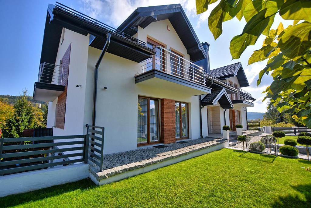 a house with a green lawn in front of it at Willa MAJA in Krynica Zdrój