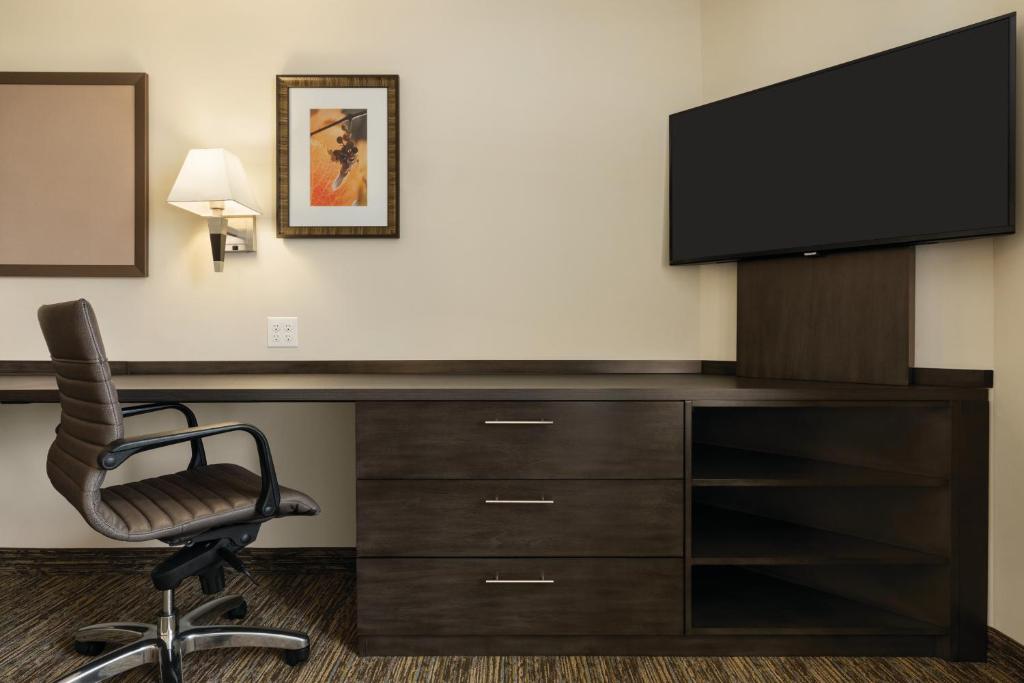 a desk with a television and a chair in a room at Park Inn by Radisson, Calgary Airport North, AB in Calgary