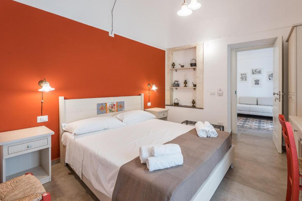 sypialnia z dużym białym łóżkiem i pomarańczową ścianą w obiekcie Il Baiocco w mieście Ragusa