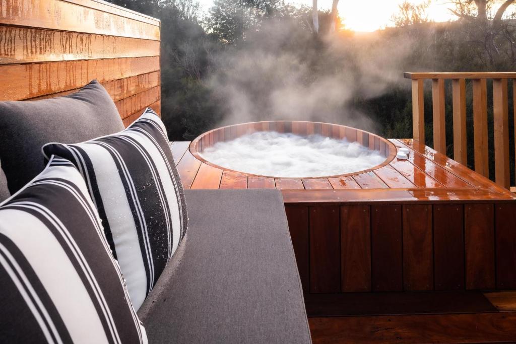 a hot tub sitting on a patio with pillows at Peppers Cradle Mountain Lodge in Cradle Mountain