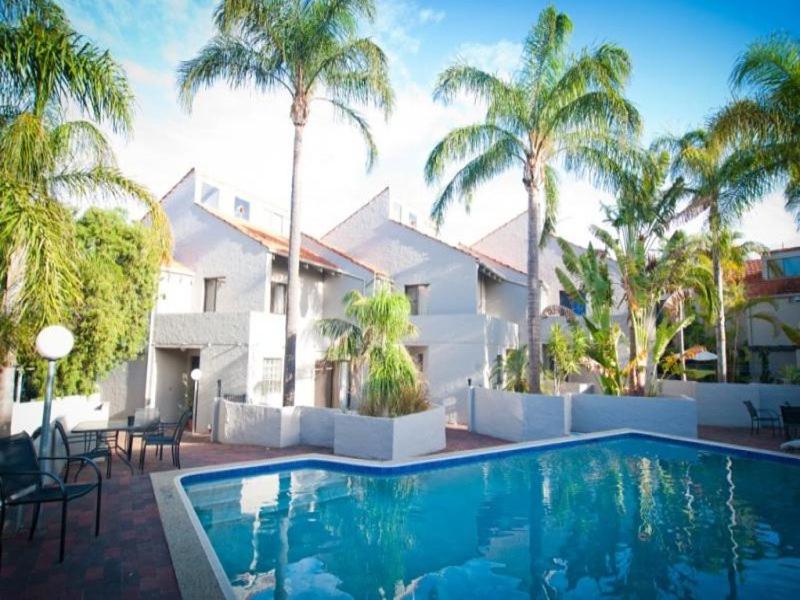 a swimming pool in front of a house with palm trees at Como Mezzanine Retreat in Perth