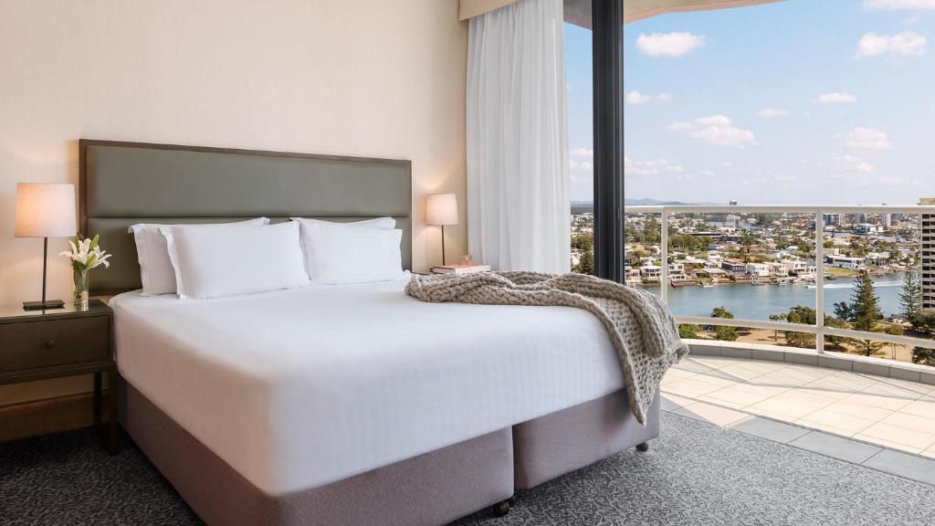a bedroom with a large bed and a large window at Oaks Gold Coast Hotel in Gold Coast
