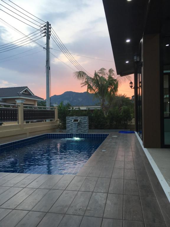uma piscina numa casa com um pôr-do-sol ao fundo em บ้านฟูจิ (Fuji House Cha-Am) em Ban Bo Prakhon