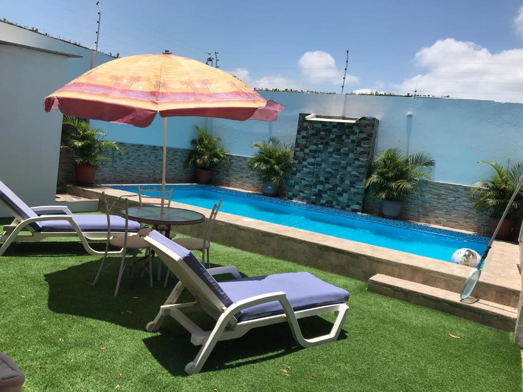 une terrasse avec une table, des chaises et un parasol dans l'établissement Casa Blue Tortuga, à Ballenita