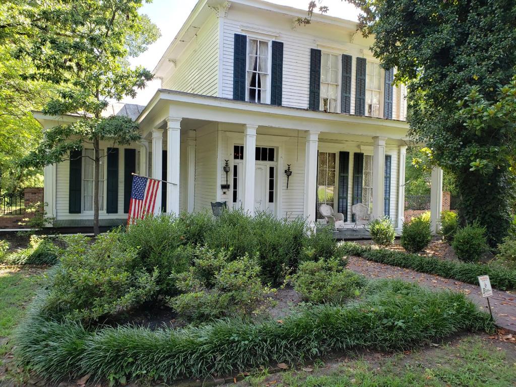 una vecchia casa con una bandiera americana nel cortile di Heritage Inn BNB a Holly Springs